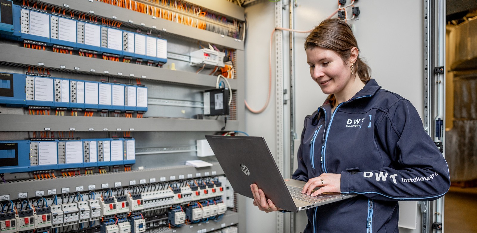 Een medewerker van DWT controleert met laptop een installatie